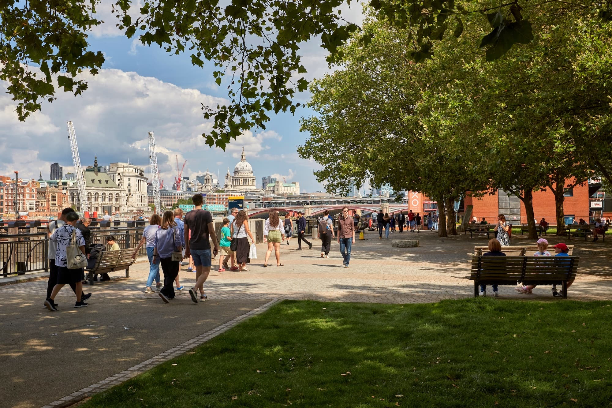Photo showing people enjoying a walk along the south bank of the River Thames in the sunshine